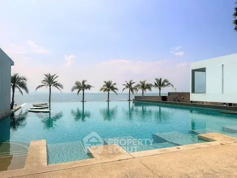 Luxurious beachfront infinity pool with stunning ocean view and palm trees.