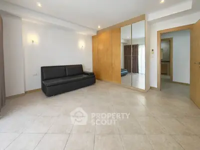 Spacious living room with mirrored wardrobe and modern sofa in a bright apartment.