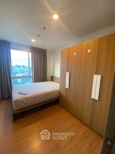 Cozy bedroom with city view, featuring a large wardrobe and wooden flooring.