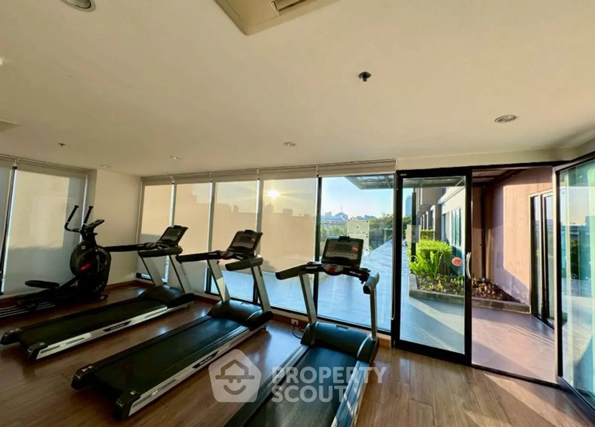 Modern gym with treadmills and outdoor view in luxury apartment complex.