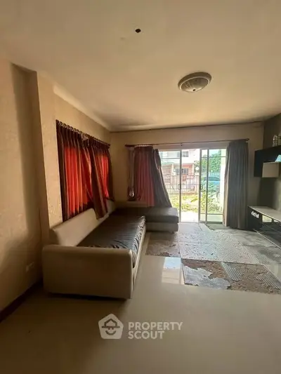 Spacious living room with large windows and modern sofa, offering a cozy and inviting atmosphere.