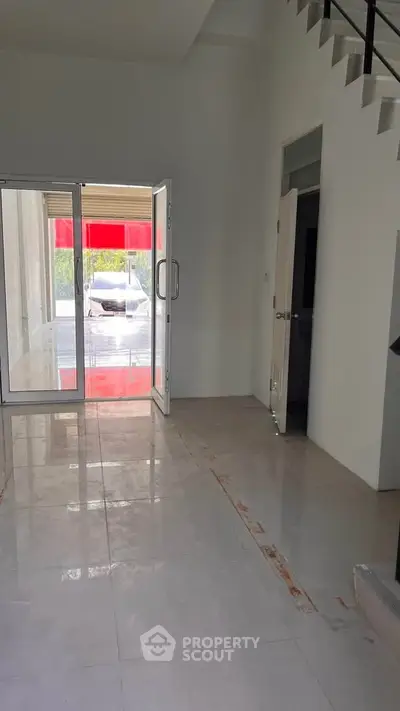 Spacious modern entrance with glass doors and tiled flooring, ideal for commercial or residential use.