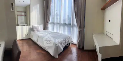 Modern bedroom with large window and wooden flooring in a stylish apartment.