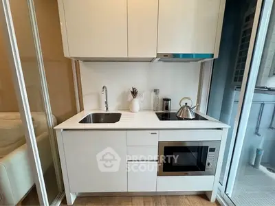 Modern compact kitchen with sleek white cabinetry and built-in appliances
