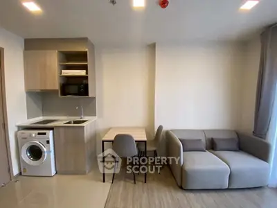 Modern compact living room with kitchenette and washing machine in cozy apartment.