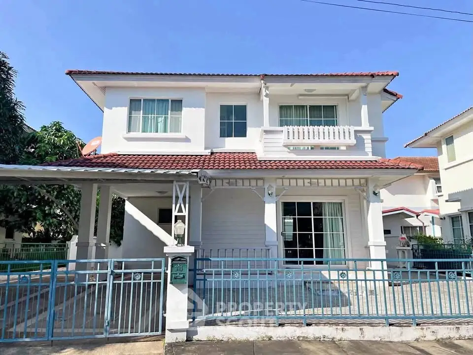 Charming two-story house with a tiled roof and spacious driveway in a serene neighborhood.