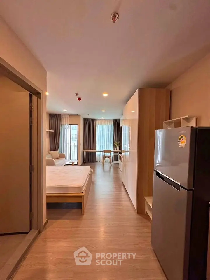 Modern studio apartment with open layout, featuring a cozy living area and sleek kitchen appliances.