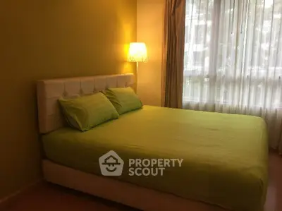 Cozy bedroom with green accents and natural light from large window.