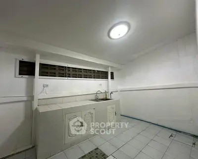 Spacious tiled kitchen with closed layout and ample storage space.