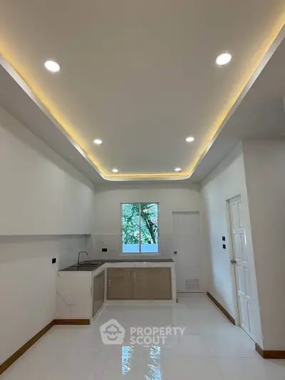 Modern kitchen with sleek design, recessed lighting, and large window for natural light.