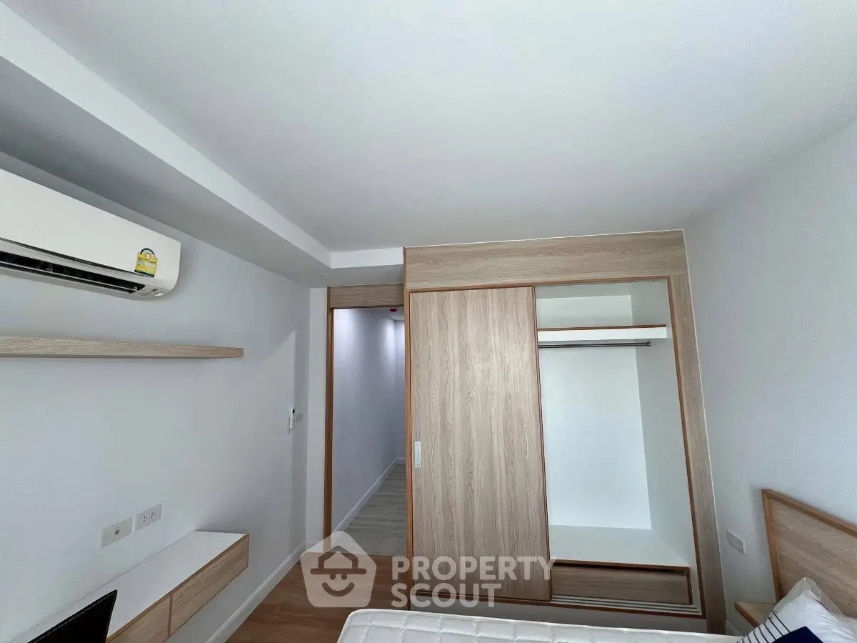 Modern bedroom with built-in wardrobe and air conditioning in a minimalist design apartment.