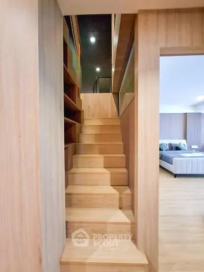 Modern wooden staircase leading to upper floor with cozy bedroom view