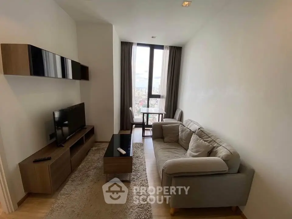 Modern living room with cozy sofa, TV, and city view from large window.