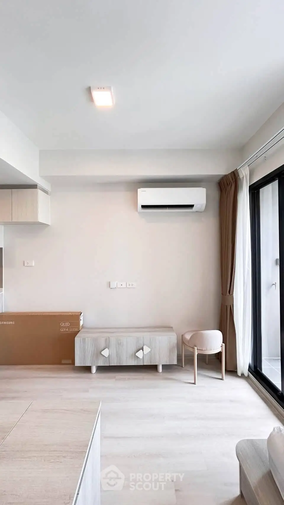 Modern living room with air conditioning and balcony access, featuring minimalist furniture and natural light.