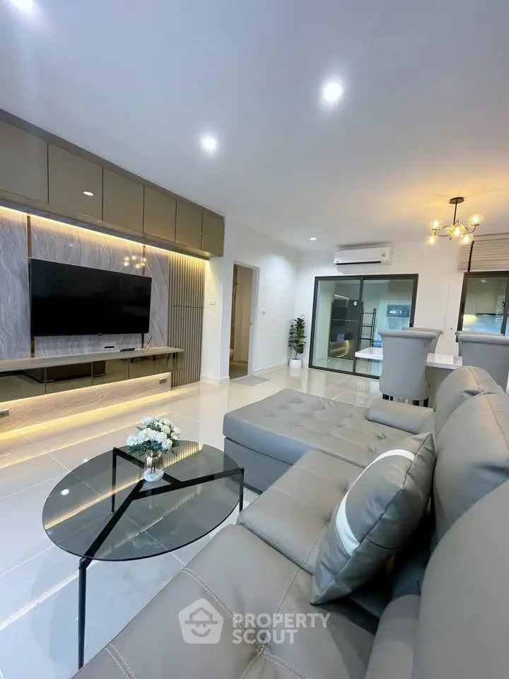 Modern living room with sleek furniture and open layout, featuring a large TV and stylish decor.