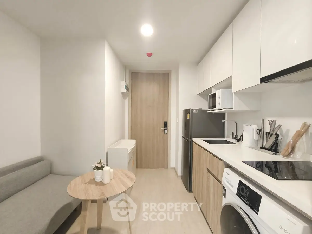 Modern compact kitchen with washing machine and sleek appliances in a cozy apartment.