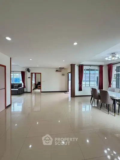 Spacious open-plan living and dining area with large windows and modern decor.