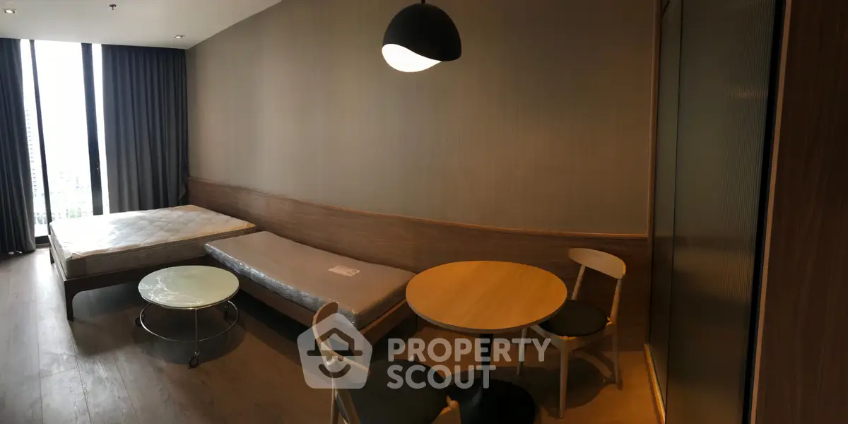 Modern studio apartment with minimalist furniture and large window view.