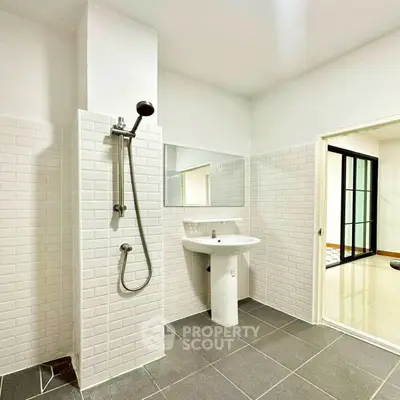 Modern bathroom with sleek design and white tiles, featuring a shower and pedestal sink.