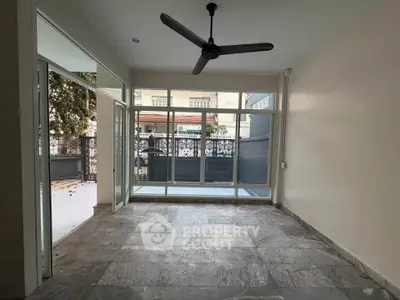 Spacious living room with large windows and ceiling fan, offering ample natural light and modern design.