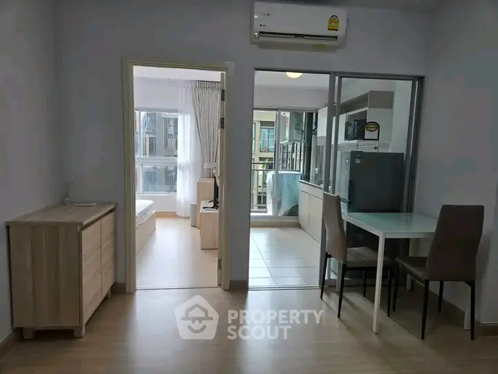 Modern apartment interior with open layout, featuring dining area and view into bedroom and balcony.