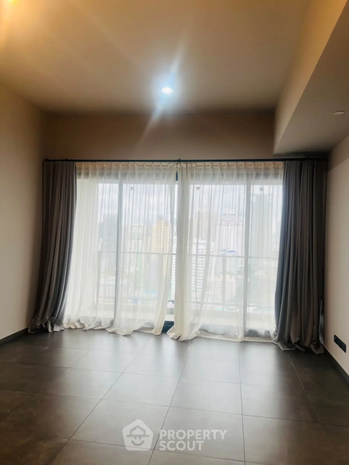 Spacious living room with large windows and city view, perfect for natural light lovers.
