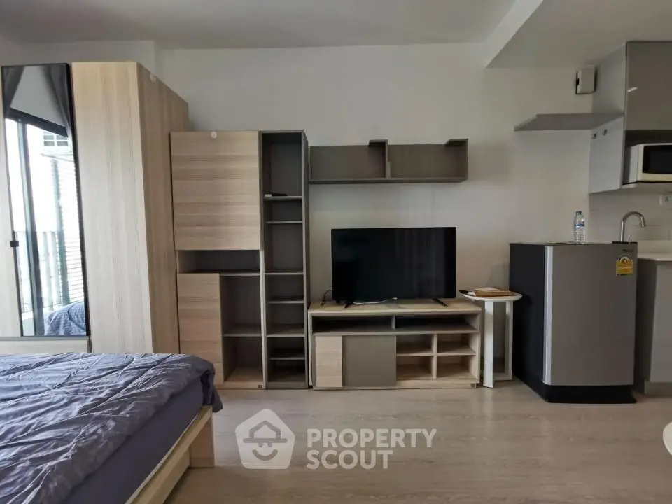 Modern studio apartment with sleek furniture and compact kitchen area.