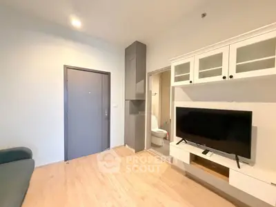 Modern living room with sleek TV unit and cozy sofa, featuring a glimpse of a stylish bathroom.