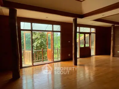Spacious wooden interior with large windows and balcony access, offering serene natural views.