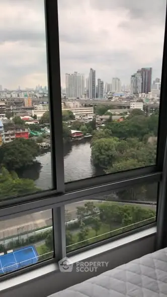 Stunning cityscape view from high-rise apartment window overlooking river and urban skyline.
