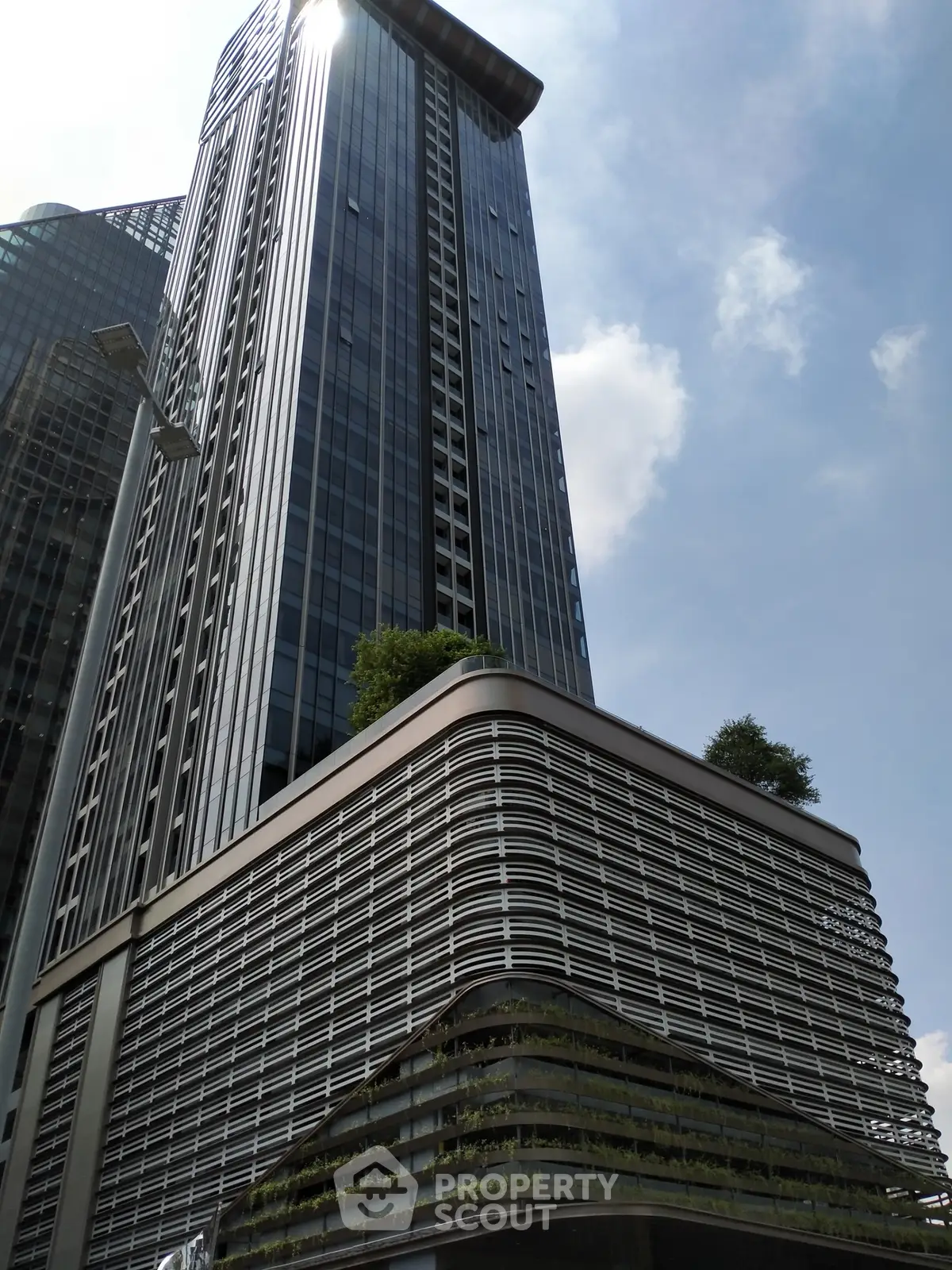 Modern high-rise building with sleek design and lush greenery in urban setting