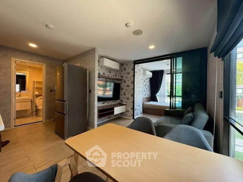 Modern open-plan living room with dining area and view into a stylish bedroom, featuring contemporary decor.