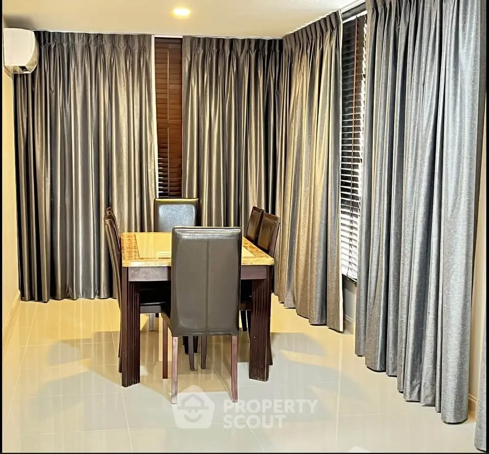 Elegant dining area with modern table and chairs, surrounded by luxurious floor-to-ceiling curtains.