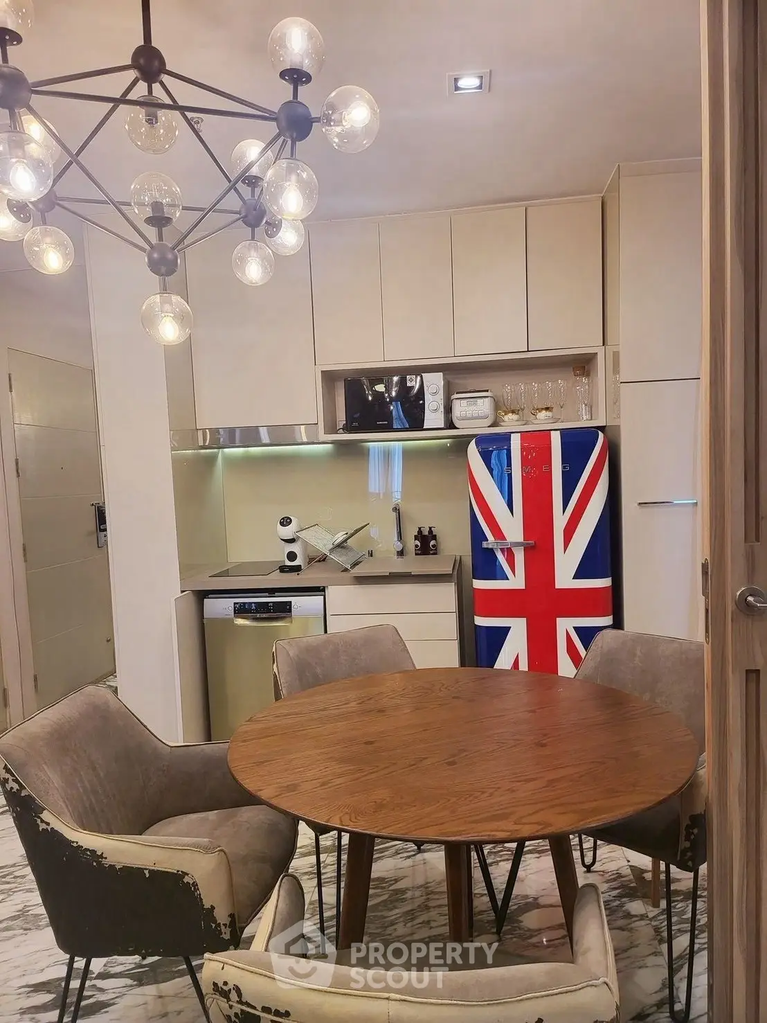 Stylish kitchen with Union Jack fridge and modern chandelier, perfect for urban living.