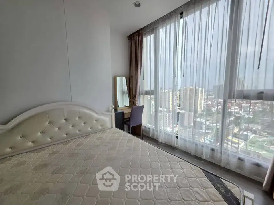 Spacious bedroom with large windows offering stunning city views, perfect for urban living.