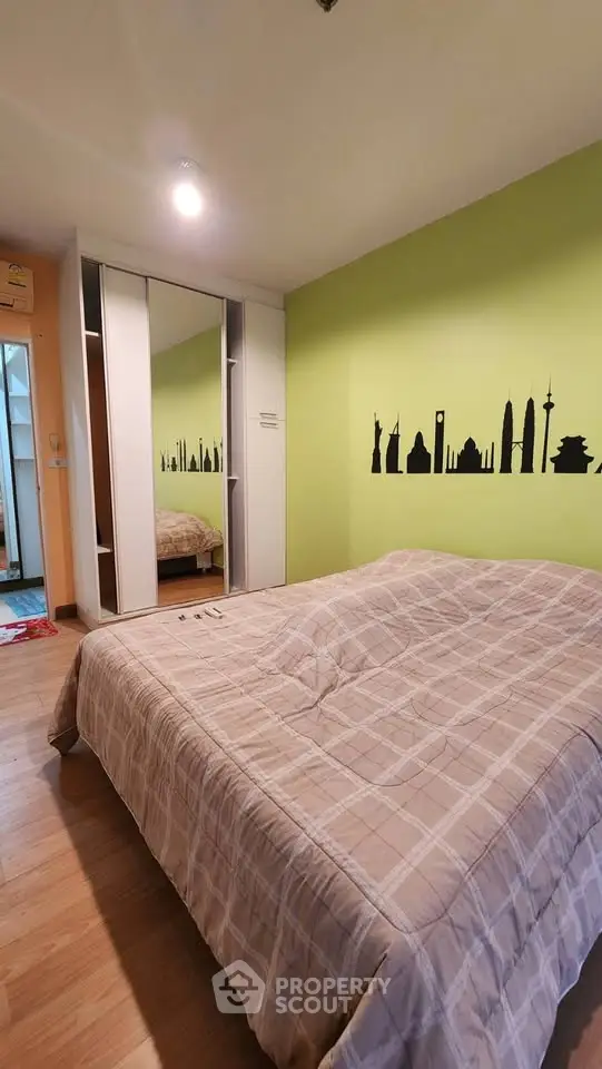 Cozy bedroom with mirrored wardrobe and cityscape wall art, perfect for urban living.
