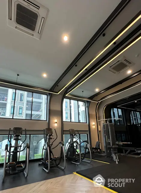 Modern gym with state-of-the-art equipment and large windows in luxury apartment complex.