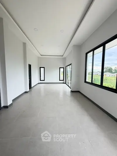 Spacious modern living room with large windows and natural light, perfect for family gatherings.