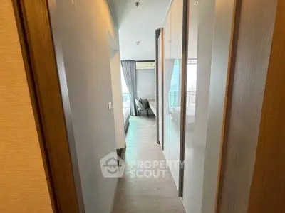 Modern apartment hallway leading to a bright bedroom with large windows and elegant decor.