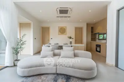 Modern living room with stylish sofa and open kitchen layout, featuring sleek appliances and elegant decor.