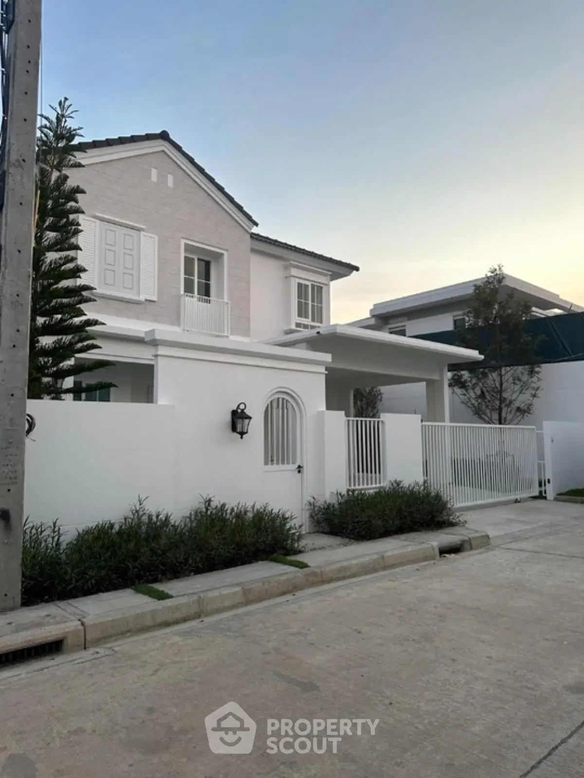 Charming modern white house with elegant facade and lush greenery in serene neighborhood.