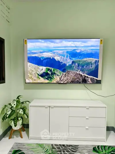 Modern living room with wall-mounted TV and sleek white cabinet