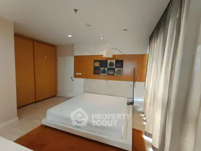 Spacious bedroom with modern decor and large windows for natural light.