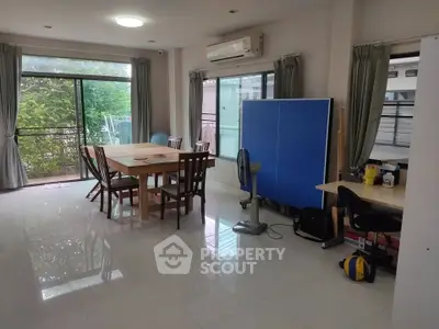 Spacious living room with dining area and large windows overlooking greenery