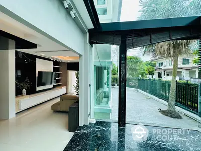 Elegant living space with seamless indoor-outdoor transition, featuring modern entertainment wall unit and polished marble flooring.