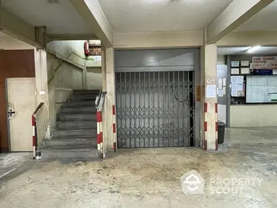 Industrial style building entrance with gated elevator and concrete stairs