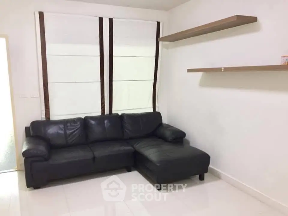 Modern living room with black leather sofa and minimalist shelves