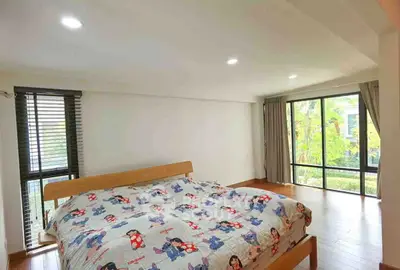 Spacious bedroom with large windows and garden view, featuring wooden flooring and cozy bed setup.
