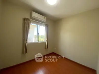 Bright empty room with wooden flooring and air conditioning, perfect for customization.