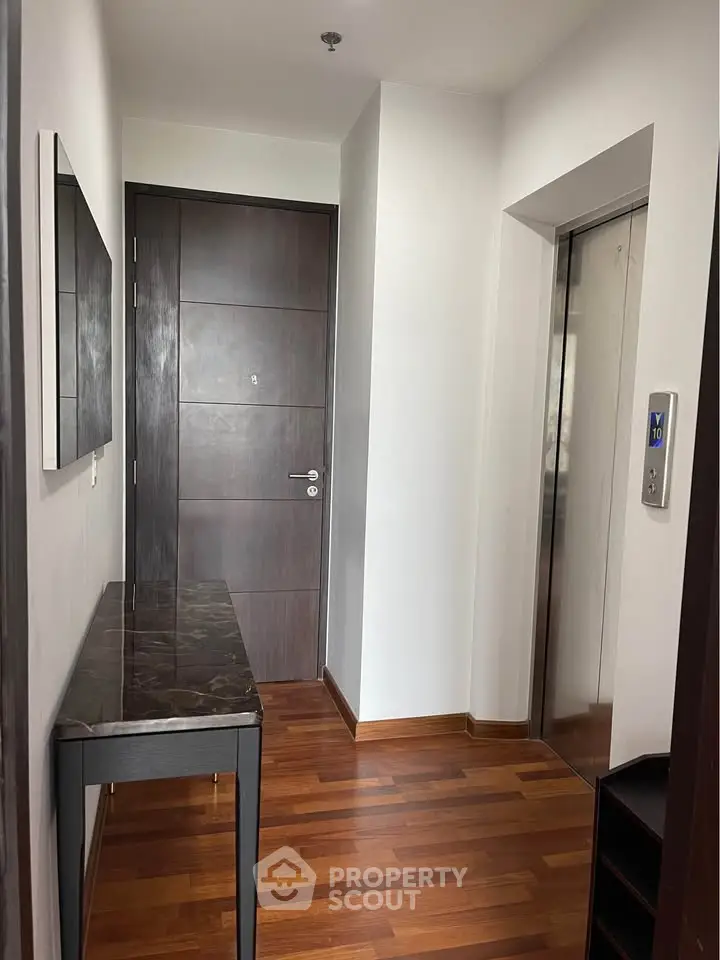 Modern apartment entrance with wooden flooring and elevator access